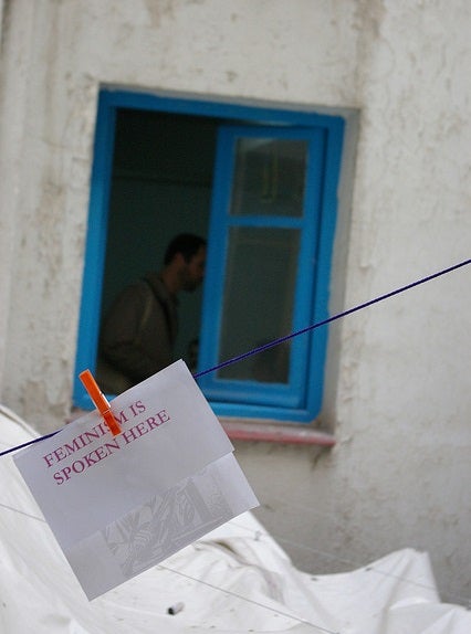 Blue window and sign with 'Feminism is spoken here' written on it