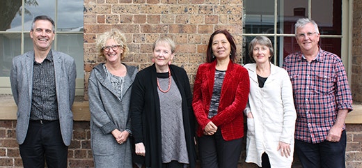Professors David Rowe, Gay Hawkins, Katherine Gibson, Ien Ang, Kay Anderson and Tim Rowse standing against the brick wall of the ICS building.