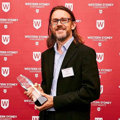Photo of Professor Donald McNeill holding a glass award.