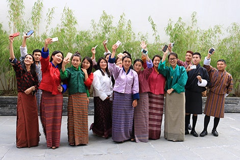 A group of young people holding mobile phones in the air.