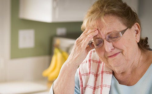 A woman touching her head with her hand as though she is in pain.