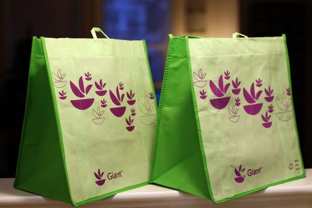 Two green reusable bags with a purple printed pattern on them.