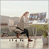 Thumbnail image of woman at a computer with outdoor view behind her.
