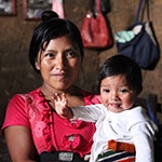 A mother, facing the camera, holds her baby. Photo ©UNICEF Guatemala/2019/Escobar.