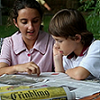 Two young children reading the newspaper