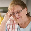 A woman touching her head with her hand as though she is in pain.
