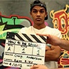 Thumbnail image of a young man behind a clapperboard and in front of a mural