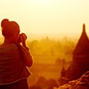 A young woman photographing a view in the sunset.