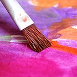 A brush painting bright colours on paper. Image by Uwe Baumann from Pixabay.