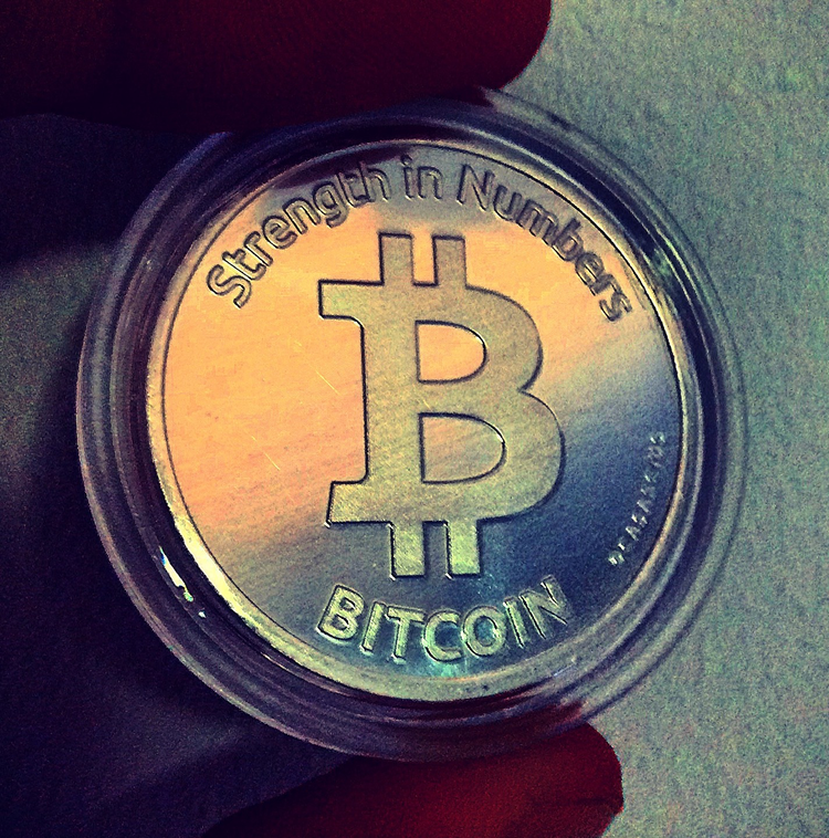 fingers holding a bitcoin