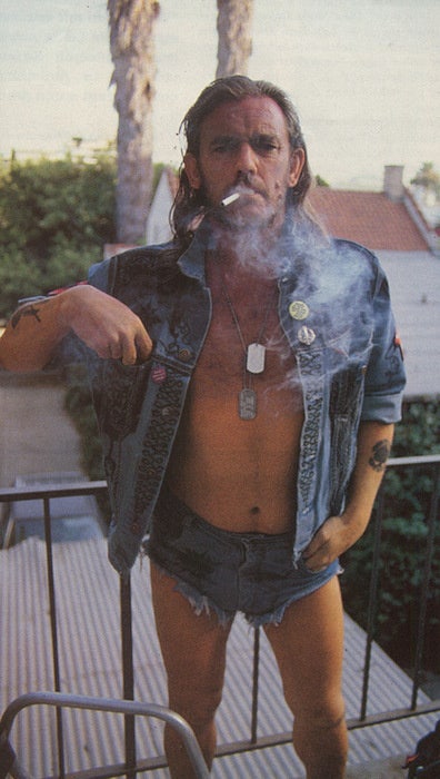 Lemmy wearing denim shorts and jacket with smoke