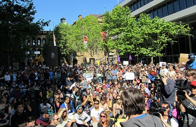 A crowd of people at Martin Place - some have signs and some have video cameras.