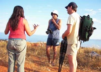 A group of three people standing by the ocean.
