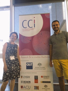 Cecilia Hilder and Luigi Di Martino standing in front of an ARC Centre of Excellence for Creative Industries and Innovation (CCI) pull-up banner.