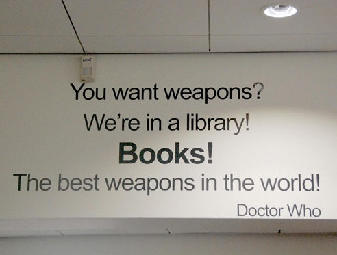 A Doctor Who quote on the wall of a library reads: 'You want weapons? We're in a library! Books! The best weapons in the world! Doctor Who'.