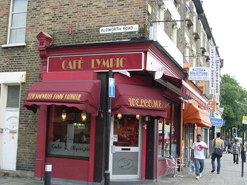 A red cafe's sign reads 'Cafe lympic'. The 'O' is missing.