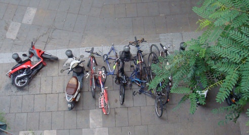 Looking down on some bikes and scooters on the pavement, some which have fallen over.