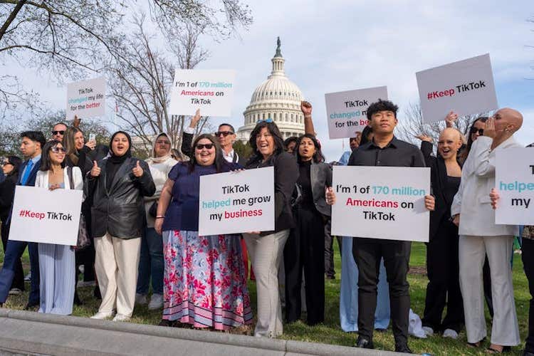 A diverse group of people holding up various placards in support of TikTok.