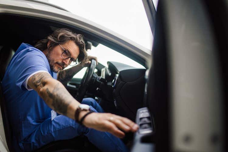 A medical worker closes the car door as he prepares to commute to work