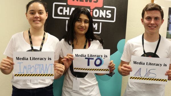 Three young people hold up worksheets which read ‘Media Literacy is’. They have completed the worksheets with the words ‘Important’, ‘To’ and ‘Us’.