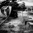 A black and white photo of a canon and barbed wire in a field.