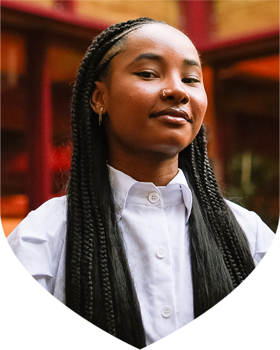 Image of young female with long blakc braided hair wearing a white collared shirt facing the camera