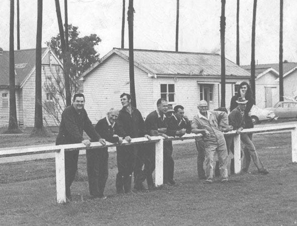 Staff members leaning on the fence near the oval [Hawkesbury Agricultural College (HAC)]