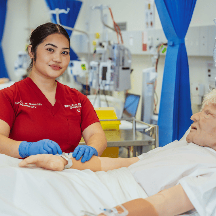 Student for the School of Nursing and Midwifery attending pretend patient.