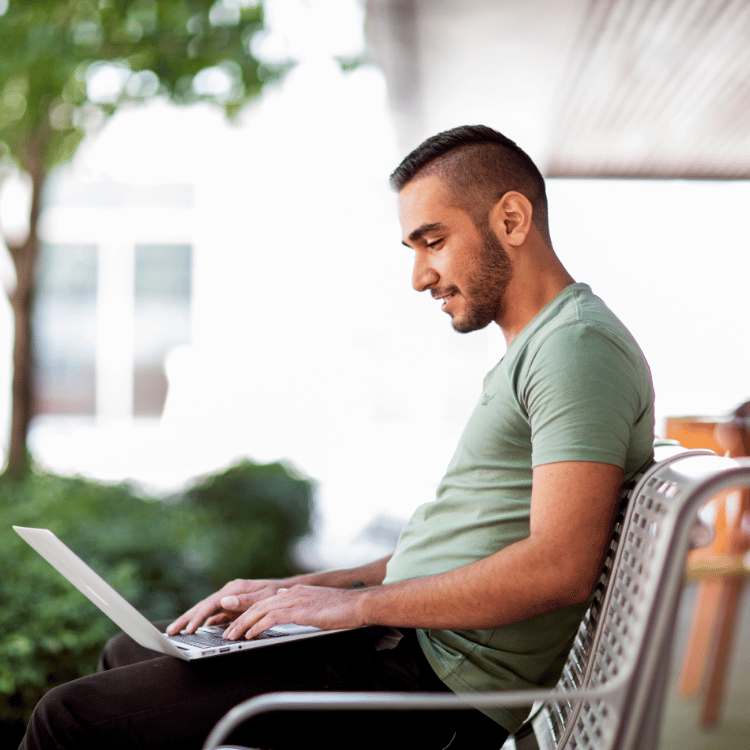 Student sitting on a bench with their laptop