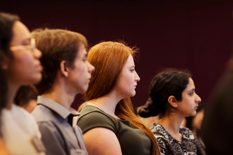 photo of four students with varying colours of skin and hair sitting in a row facing the same way