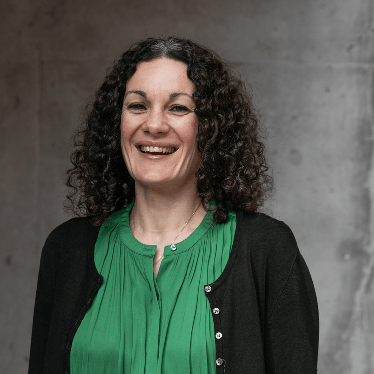 A woman with curly brown hair smiles at the camera.