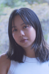 Helen Tran wears a white singlet and has short black hair. She looks at the camera,.