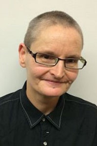 Portrait photograph of a woman with very short hair and glasses